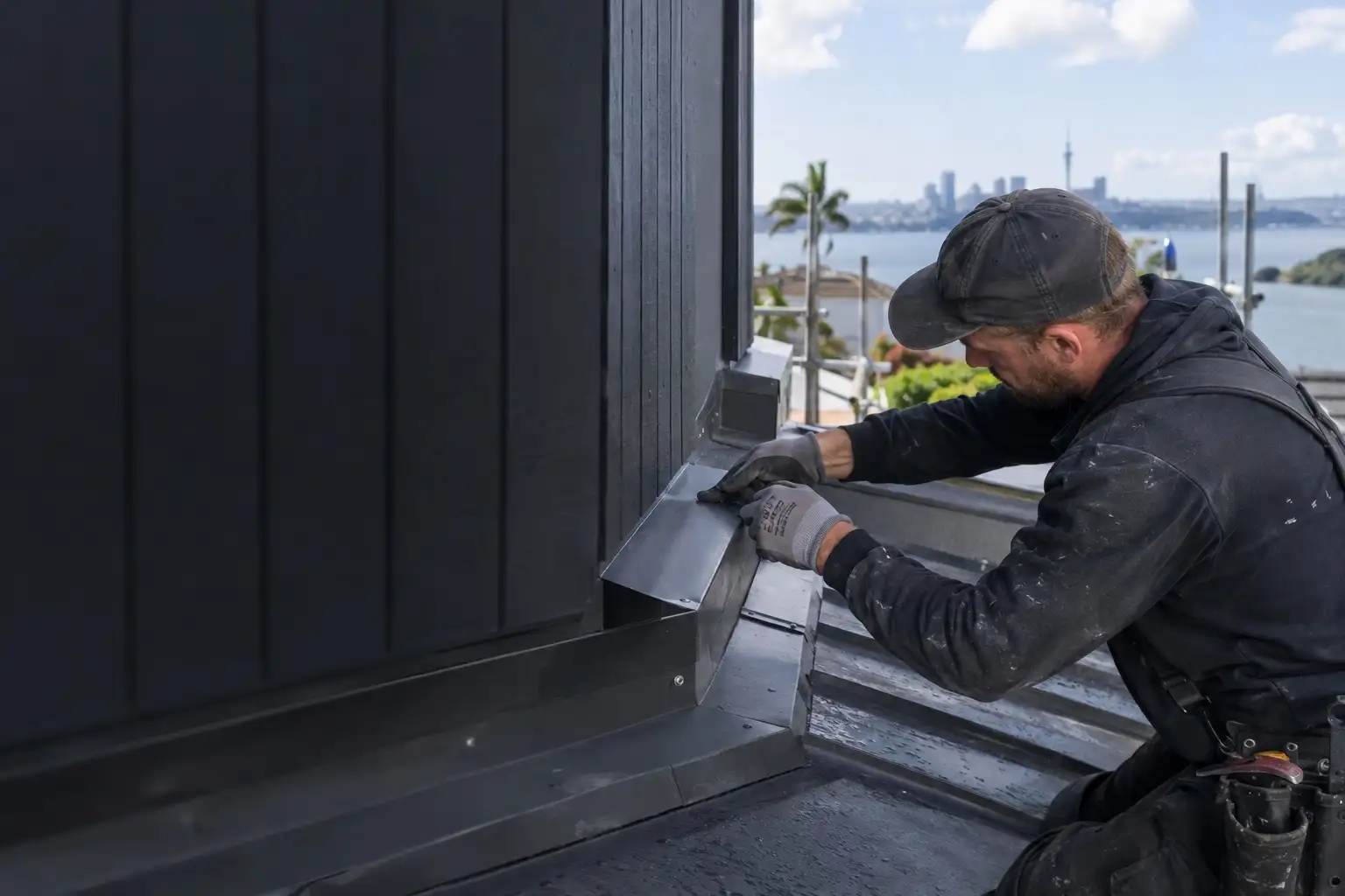 Roofer installing a custom folded flashing at a wall junction